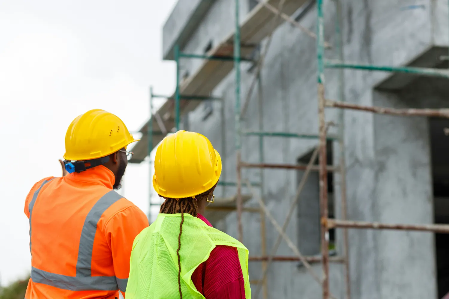 people in hardhats and vests looking at building